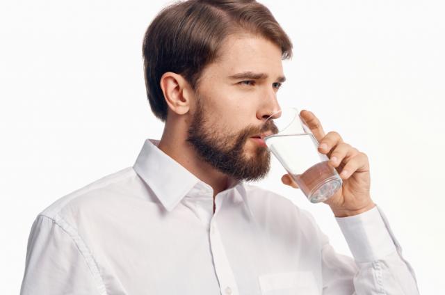 Un homme qui boit un verre d’eau